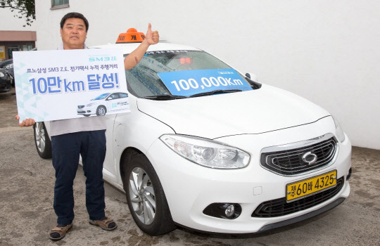 르노삼성 전기차 SM3 Z.E.로 10만㎞를 달린 주인공인 SM3 Z.E. 택시 1호 고객 김원홍씨가 기념촬영을 하고 있다. <르노삼성자동차 제공>